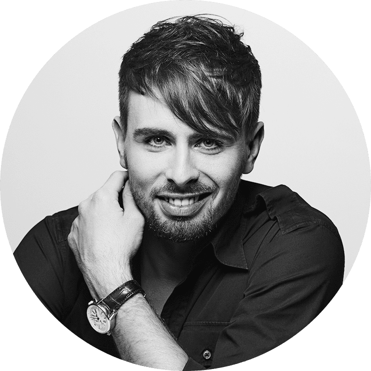 Kuba Kossut, Global CEO of Adlook, in a black and white portrait smiling with hand resting on neck, wearing a watch and dark shirt.